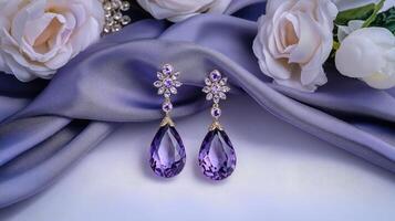 Purple earrings with diamonds on a blue cloth photo