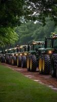A row of green tractors parked on a dirt road photo