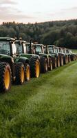 A row of green tractors parked in a field photo