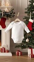 A white baby bodysuit hanging from a clothesline near a christmas tree photo