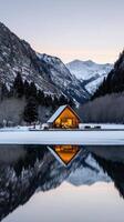 A cabin sits on the shore of a lake surrounded by mountains photo
