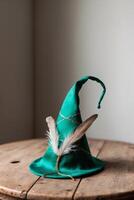 A green wizard hat with feathers on top of a wooden table photo