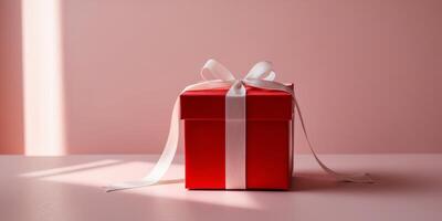Red gift box with white ribbon lying on pink background illuminated by natural light creating shadows. photo
