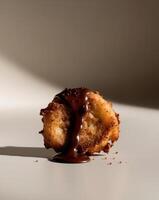 A chocolate covered doughnut sitting on a white surface photo