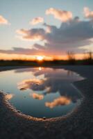 A puddle of water with the sun setting in the background. photo