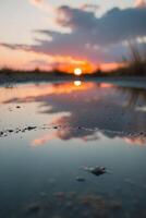 A puddle of water with the sun setting in the background. photo