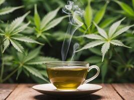 A cup of marijuana tea is sitting on a table with a leafy green background. photo