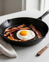 A fried egg and bacon breakfast in a frying pan looks appetizing. photo