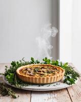 A savory mushroom quiche topped with fresh herbs and nestled on a rustic wooden surface. photo