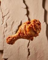 A fried chicken wing is shown in front of a wall photo