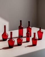 A collection of red glass bottles placed on a flat surface photo