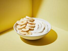a bowl of yogurt with sliced bananas on a bright yellow background photo