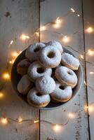 A Bowl Filled with Sweet Doughnuts Covered in Powdered Sugar and Surrounded by a String of Warm Lights on a Wooden Surface photo