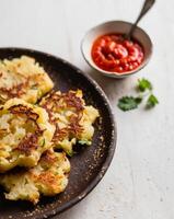 A plate of potato pancakes with a bowl of sauce photo