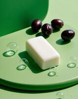 A bar of soap is on a green surface with a few olives and some bubbles photo