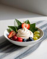 A bowl of yogurt with fruit and leaves on a marble surface photo
