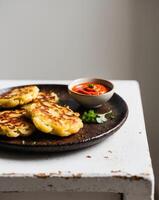 A plate with some potato pancakes and a bowl of sauce photo