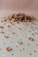 pastel pink canvas adorned with scattered rose petals and golden heart confetti softly lit and surrounded by copy space photo