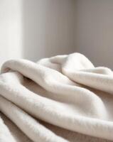 A white blanket is folded on top of a bed photo