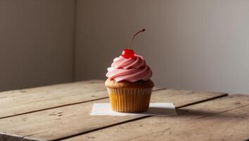 A cupcake with pink frosting on top on a wooden table photo