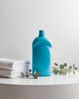 Blue plastic detergent bottle mockup standing on white surface with clean towels and eucalyptus branches photo