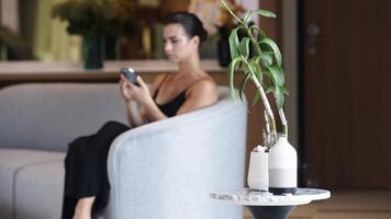 The cold steam is flowing up from the aroma diffuser on a table. Modern air humidifier device at workplace. Space for text. Person using smartphone for work and enjoying aromatherapy video