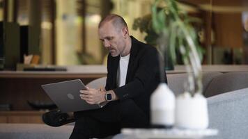 Cold steam is flowing up from the aroma diffuser on a table. Modern air humidifier device at workplace. Man using computer, laptop works on internet and enjoying aromatherapy video