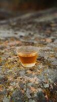 A Glass Filled with a Beautiful Amber Beverage Elegantly Resting on a Textured Rock Surface photo