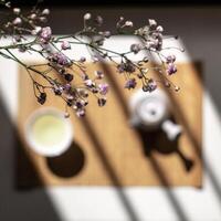 An Elegant Tea Setup Surrounded by Flowers and Gentle Shadows Enhancing the Aesthetic photo