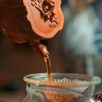 Artisan Tea is Carefully Poured from a Beautiful Traditional Clay Pot for Enjoyment and Relaxation photo