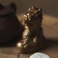 A Stunning Bronze Guardian Dragon Statue Positioned Gracefully on a Wooden Surface photo