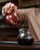 An Artisan Teapot Elegantly Pouring into a Glass Carafe, Creating a Captivating Experience photo