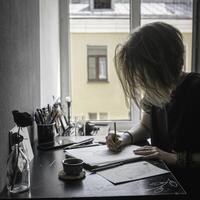 A creative workspace featuring an artist at their desk engaged in the act of drawing thoughtfully photo