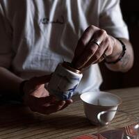 The Art of Tea Preparation Gently Pouring Leaves from a Container for Enjoyment and Calmness photo