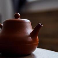 An elegant clay teapot beautifully displayed on a rustic wooden surface, enhancing its charm photo