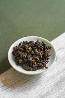 A Dried Herbal Mixture Arranged Neatly in a Small Bowl Set Upon a Rustic Wooden Surface photo
