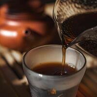 Pouring a fragrant Tea from a beautiful Glass Teapot into a delicate Cup for enjoyment photo
