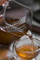 Pouring Tea from a Glass Pot into a Small Elegant Cup for a Refreshing Experience photo