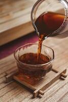 The process of pouring hot tea into a beautifully crafted glass cup filled with warmth photo