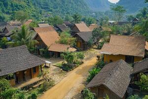 Aerial view of a rural village with traditional houses, dirt roads, and lush green surroundings. photo