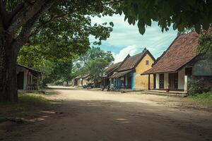 Dusty village street lined with traditional houses under leafy trees. photo