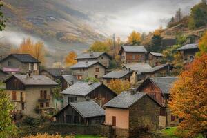 Misty mountain village in autumn with stone houses and colorful foliage. photo