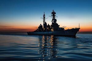 Warship silhouetted against a sunset over calm waters. photo