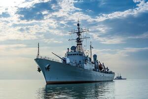 Military ship anchored in calm waters under cloudy sky. photo