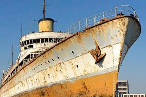 Rusty ship with peeling paint against a clear blue sky. photo