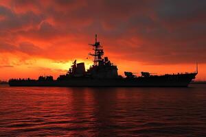 Warship silhouetted against a vibrant sunset. photo