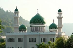 Elegant mosque with green domes and minarets against a mountain backdrop. photo
