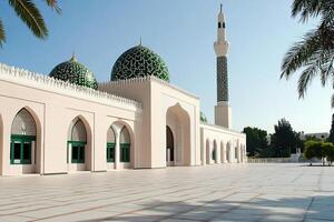 Elegant mosque with green domes, minaret, and spacious courtyard under a clear sky. photo