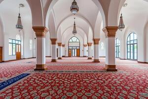 Empty mosque interior with arched ceilings, pillars, and ornate carpet. photo