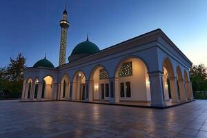 Illuminated mosque at dusk, showcasing architectural details and tranquil courtyard. photo